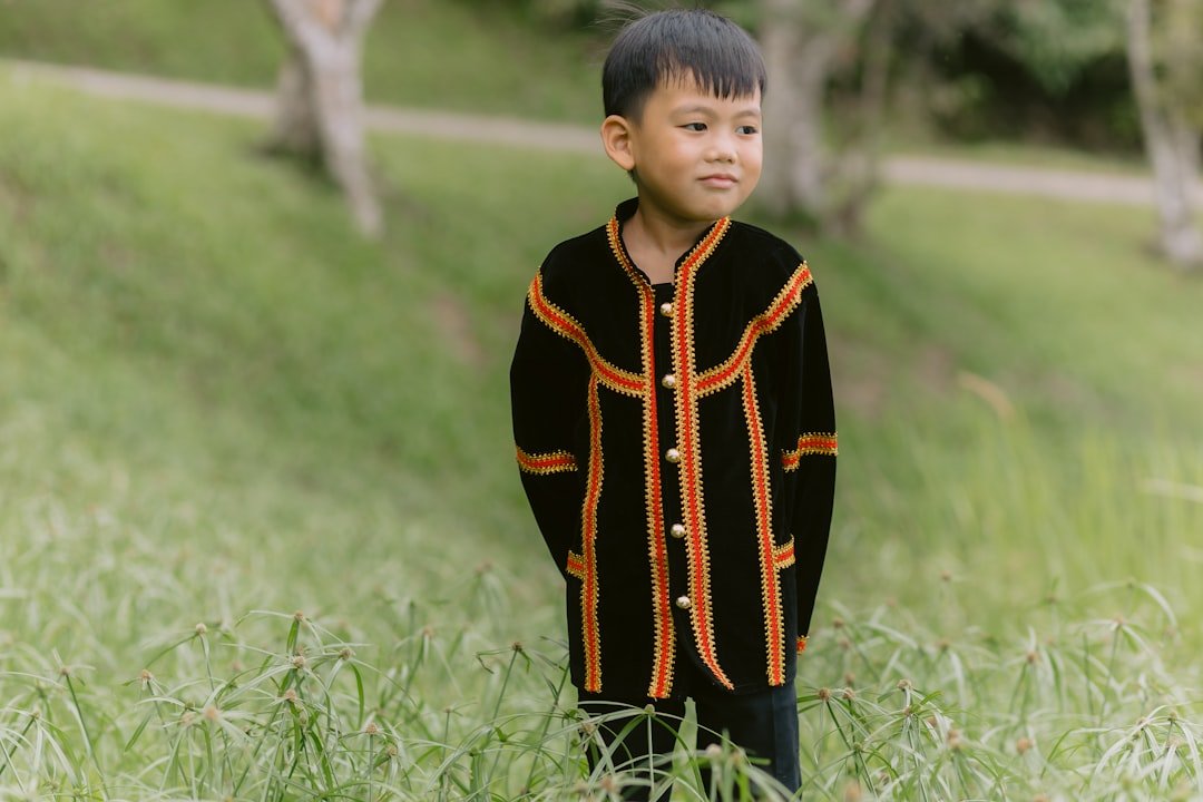 A boy poses outdoors in traditional clothing.