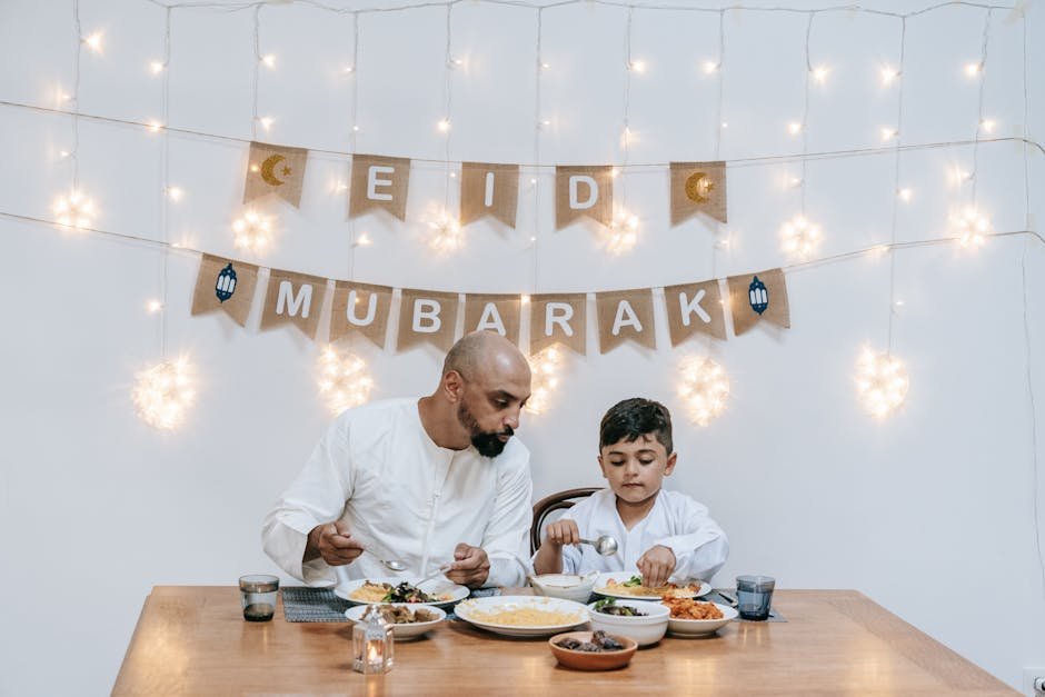 A father and son enjoy a meal together during an Eid celebration with festive decor.