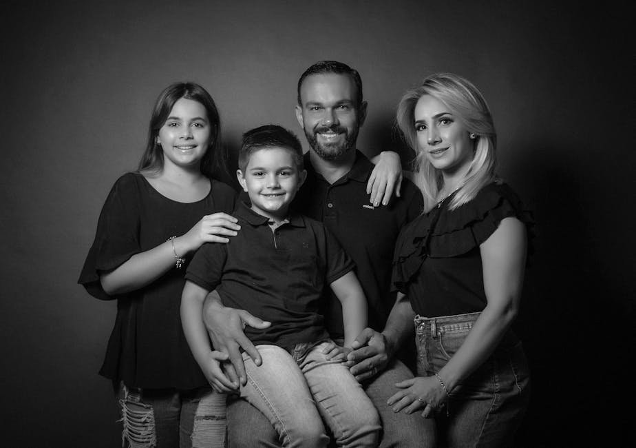 A joyful black and white family portrait featuring two adults and two children, all smiling.